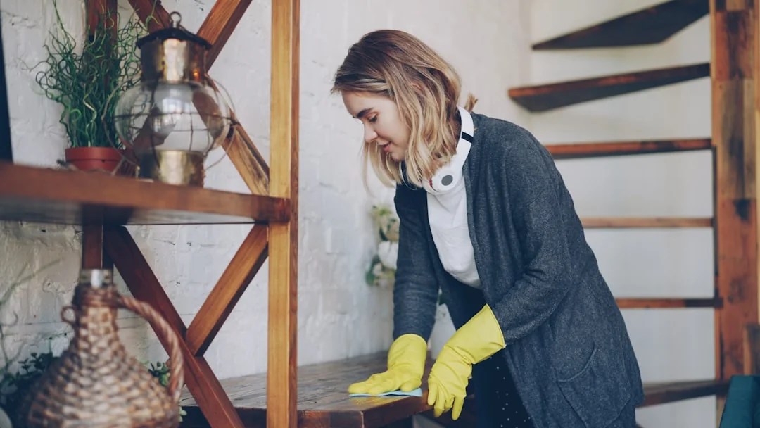 A professional cleaner in protective gear vacuuming the floor in a modern living room.